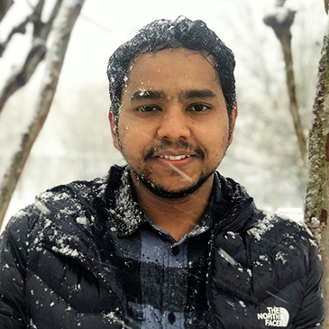Dr. Dinesh Phuyal standing outside in a winter coat as snow lightly falls.