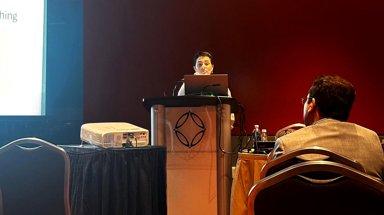 Dr. Andressa Freitas stands at a podium, presenting her research at the annual ASA-CSSA-SSSA Meetings in St. Louis, MO