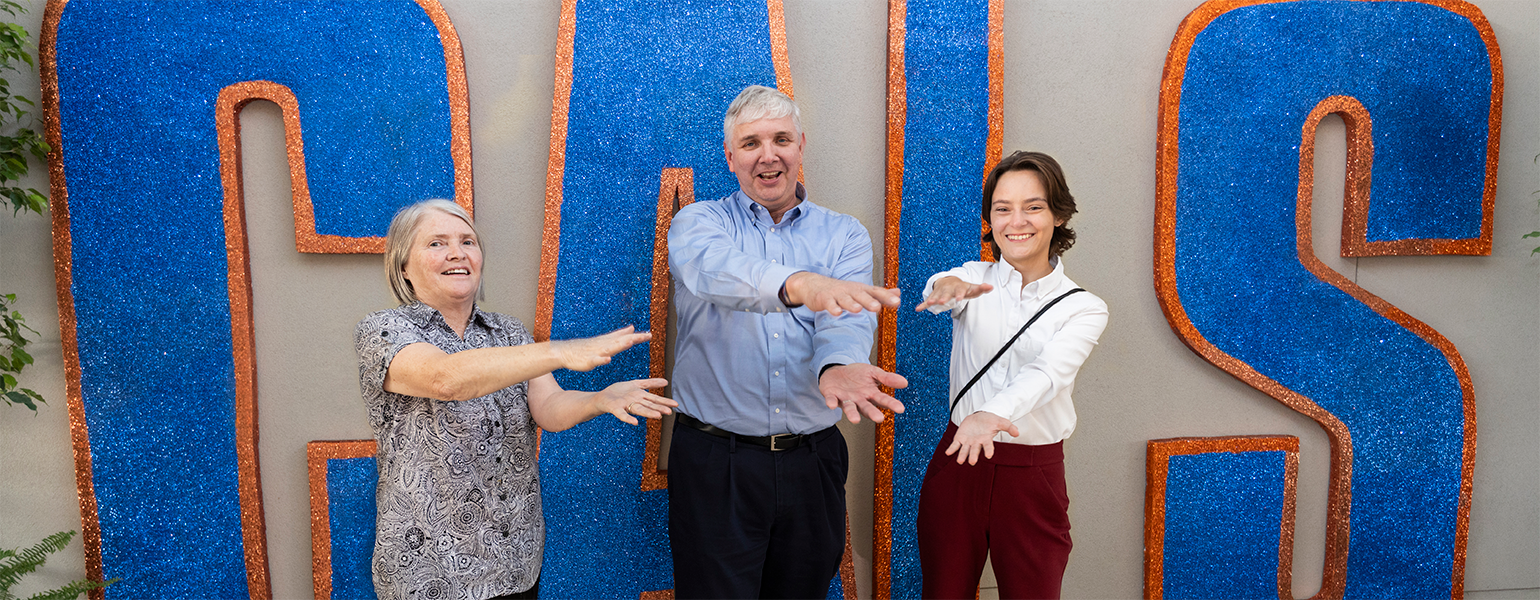 A college student stands with two faculty members at an awards ceremony, doing the University of Florida