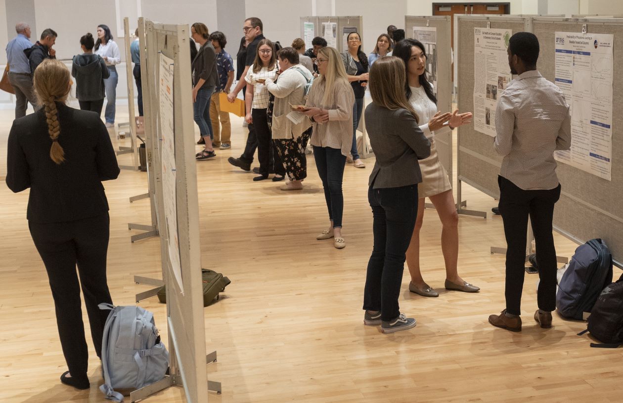 College students standing at a research poster event.