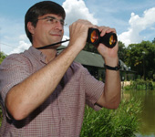 Mark Hostetler, an extension wildlife specialist with the University of Florida's Institute of Food and Agricultural Sciences, looks for birds on Bivens Arm, an urban lake in Gainesville, Fla. - Thursday, July 1, 2004. Hostetler and graduate student Ashley Traut conducted a four-month bird count on four urban lakes in central Florida - and found that waterbirds seem to prefer feeding along developed shoreline. (UF/IFAS Photo:Marisol Amador)